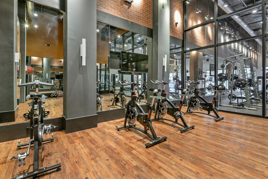 a gym with weights and cardio equipment on a wooden floor