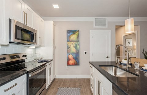 A kitchen with black countertops and white cabinets.