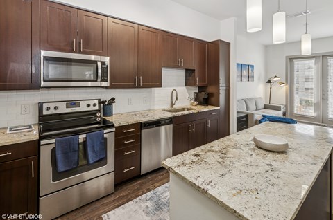A kitchen with brown cabinets and a granite countertop.
