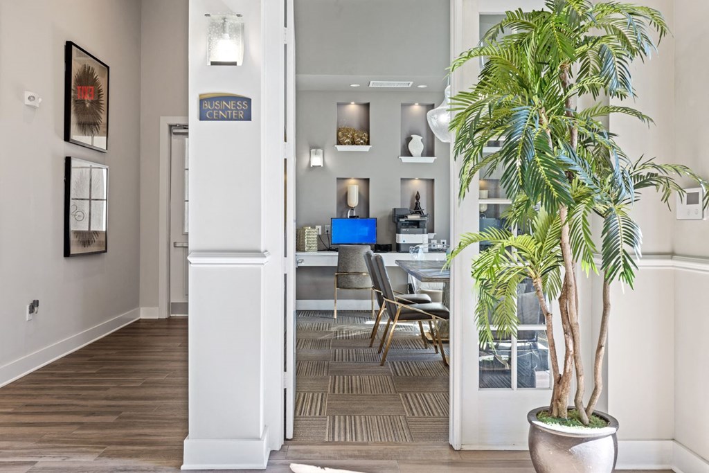 A room with a plant, chairs and a sign that says Business Center.
