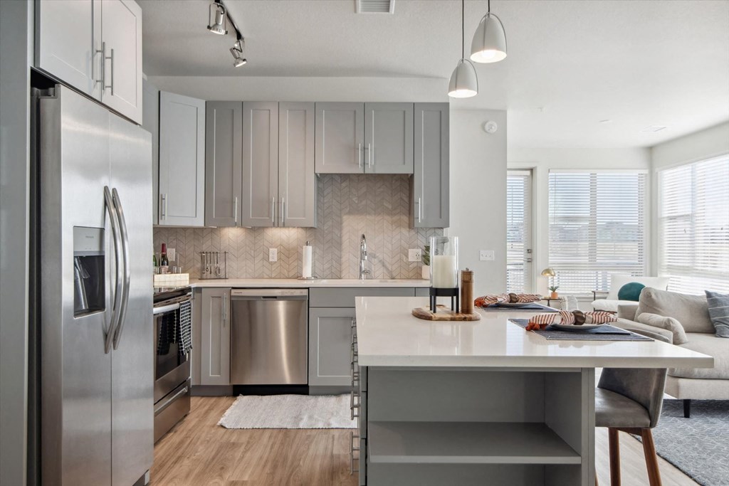 A modern kitchen with a large island and stainless steel appliances.