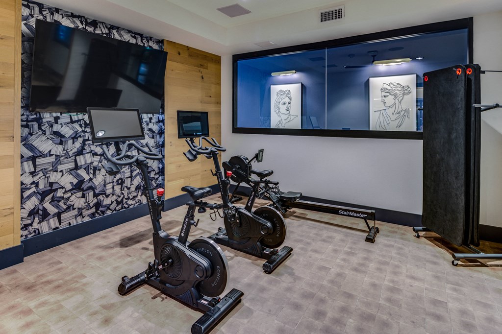 a workout room with exercise bikes and a tv