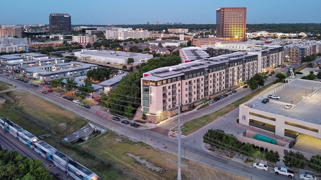 A train is passing by a highway in a city.