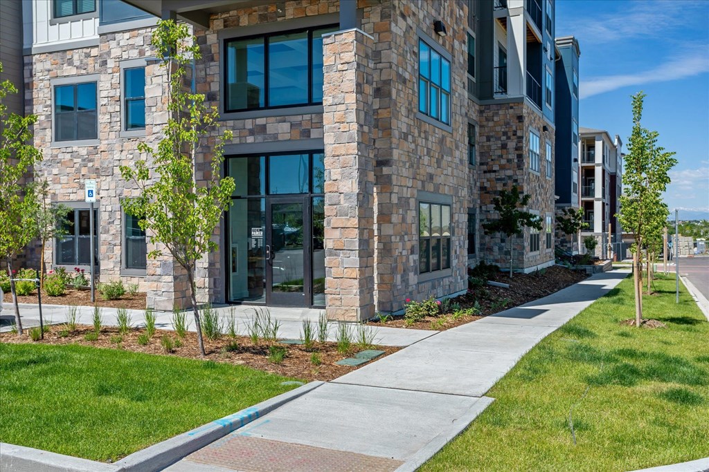 an exterior view of an apartment building with a sidewalk and grass