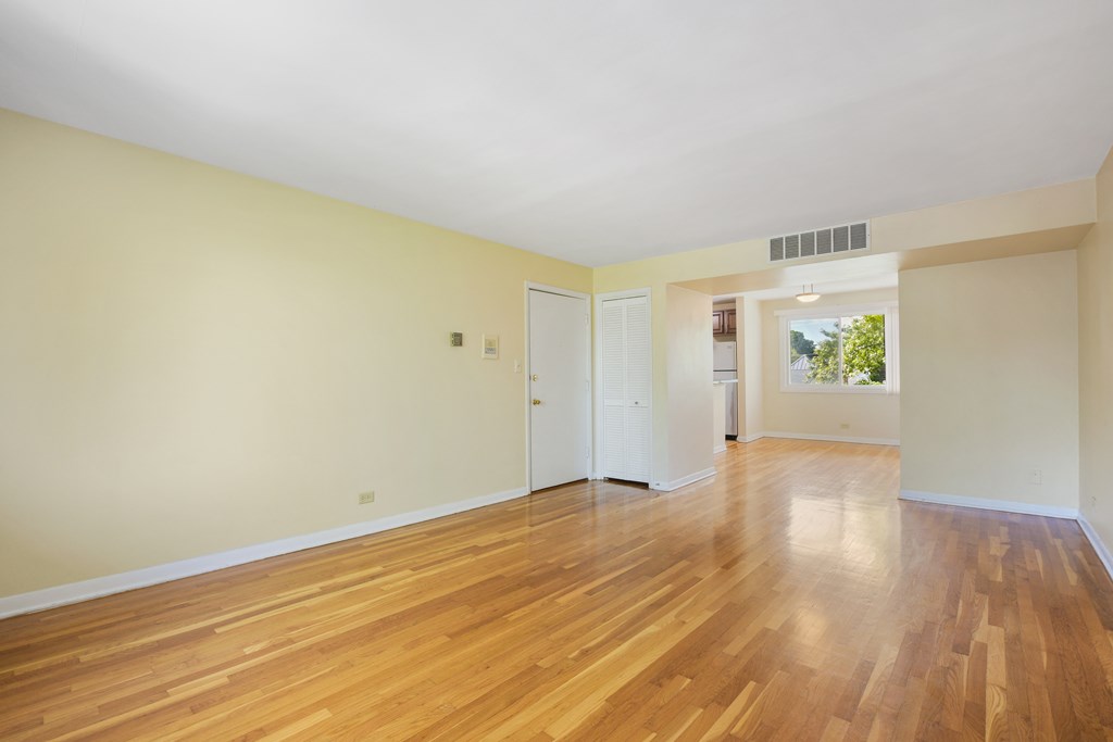 an empty living room with wood floors and white walls
