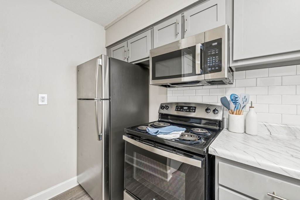 A kitchen with a stainless steel refrigerator, microwave, and oven.