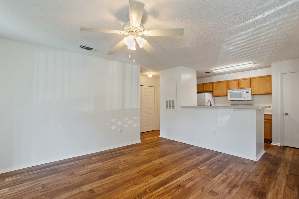 A room with a ceiling fan and wooden floors.