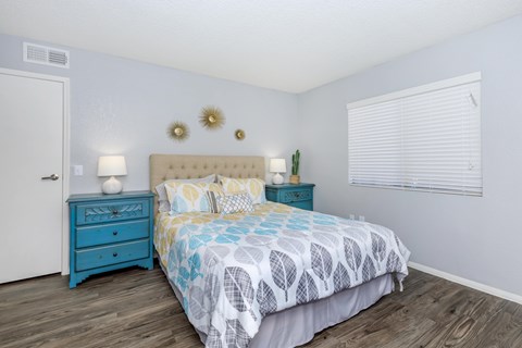 A bedroom with a blue bed and a white wall.