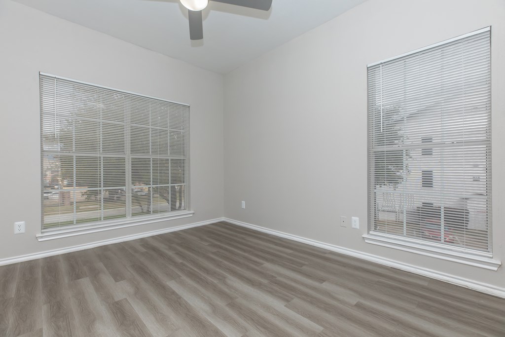 a bedroom with two windows and a ceiling fan