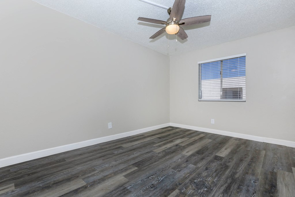 an empty living room with wood floors and a ceiling fan