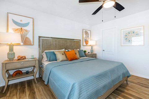 A bedroom with a bed, nightstand, and a ceiling fan.