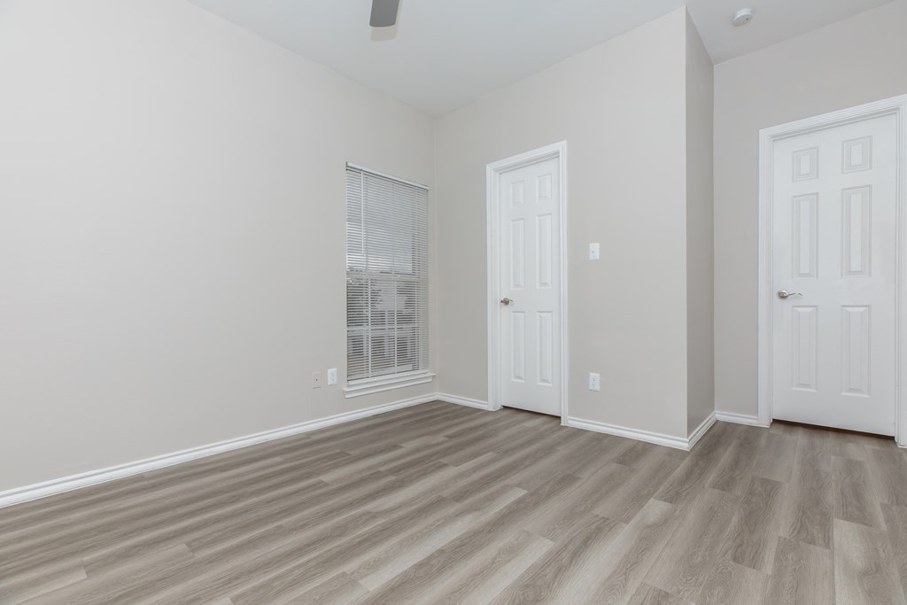 a bedroom with hardwood flooring and two doors
