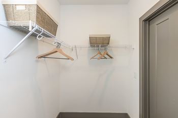A white closet with a shelf and two hangers.