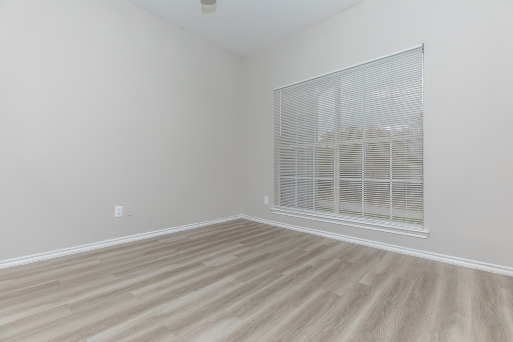 a bedroom with hardwood floors and a large window