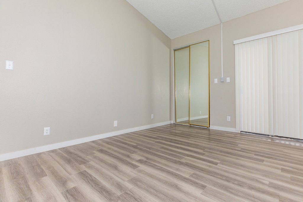 a bedroom with hardwood floors and a large window
