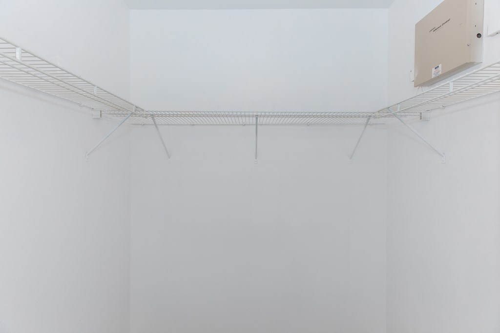 a corner of a room with white walls and a wire rack hanging on the wall