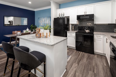 A kitchen with a black refrigerator and white cabinets.