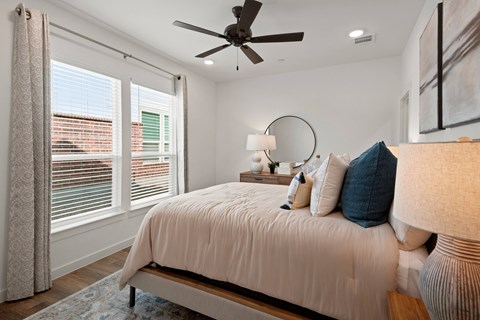 A bedroom with a bed, a ceiling fan, and a window with curtains.