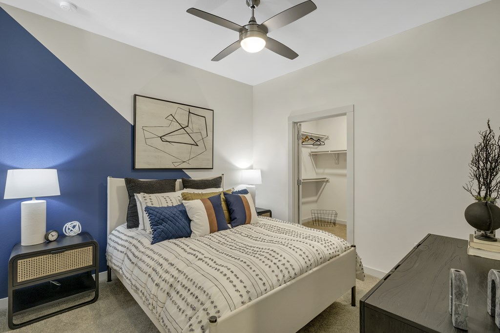 A bedroom with a bed, nightstand, and a ceiling fan.