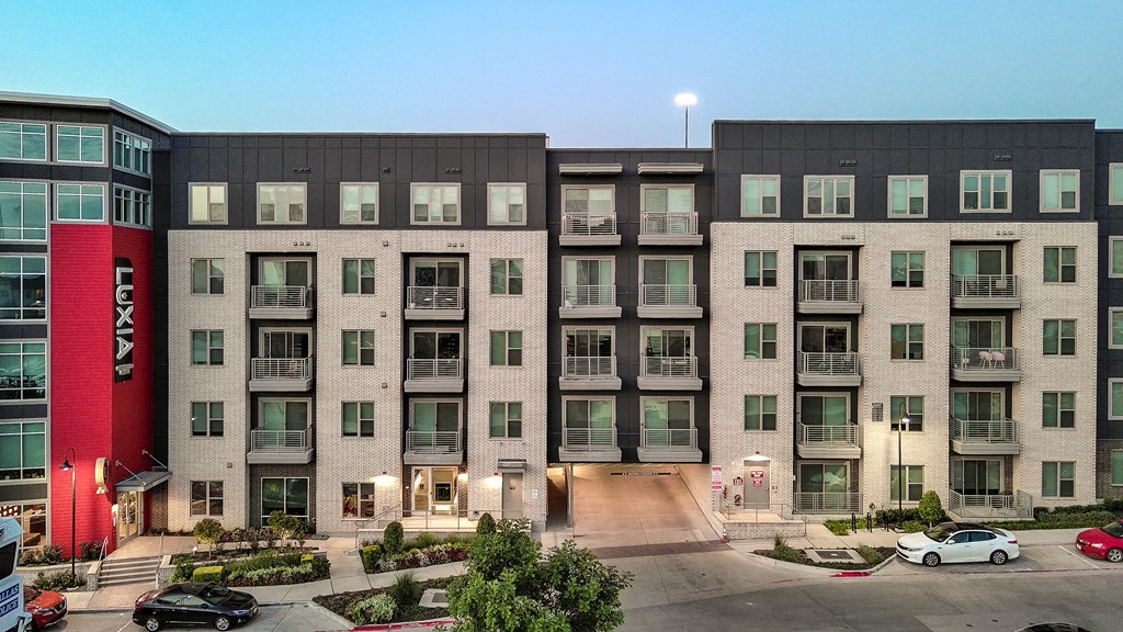 A large multi-story building with a red and black exterior and a parking lot in front.