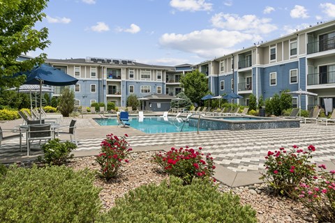 A pool surrounded by a patio with chairs and umbrellas.