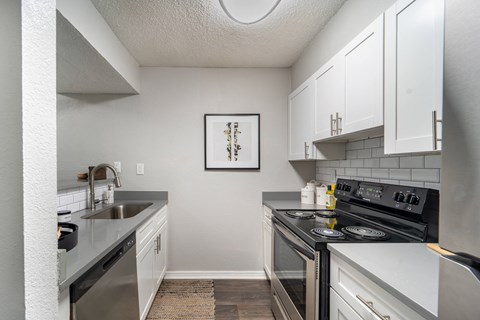 A kitchen with white cabinets and a framed picture on the wall.