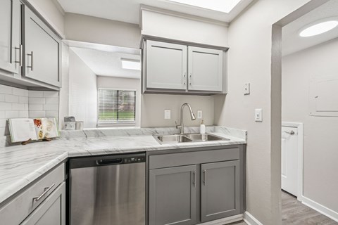 A kitchen with a stainless steel dishwasher and a white countertop.