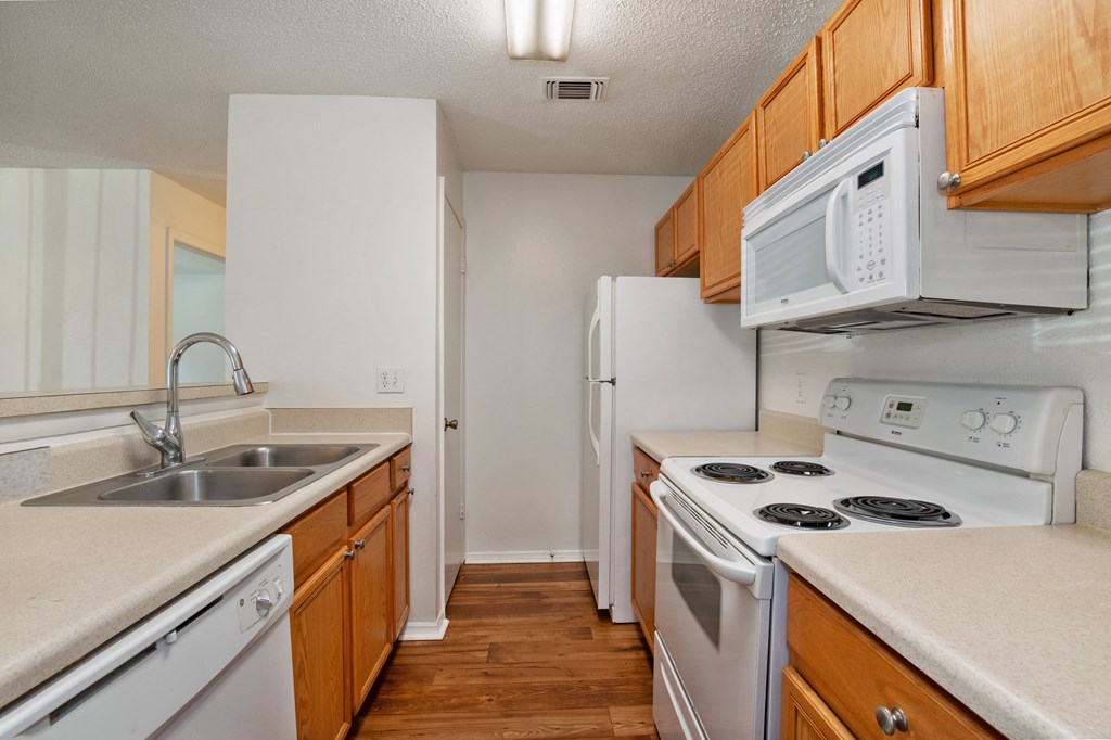 A kitchen with white appliances and wooden cabinets.