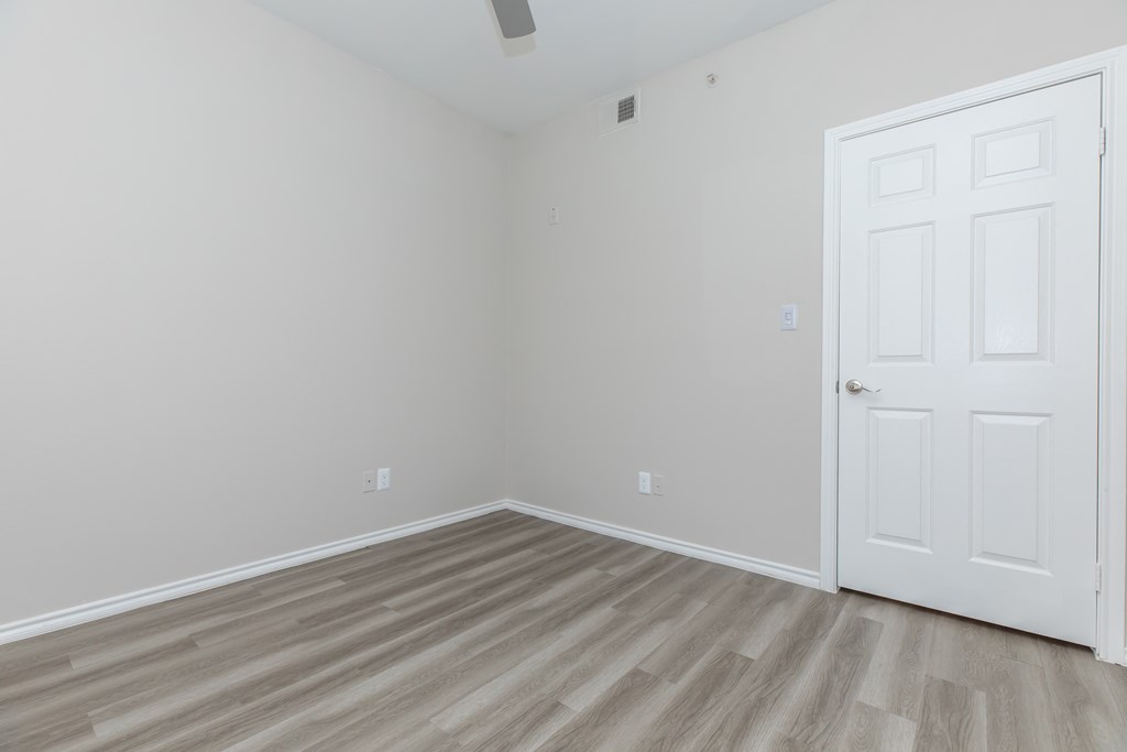 a bedroom with hardwood floors and a white door