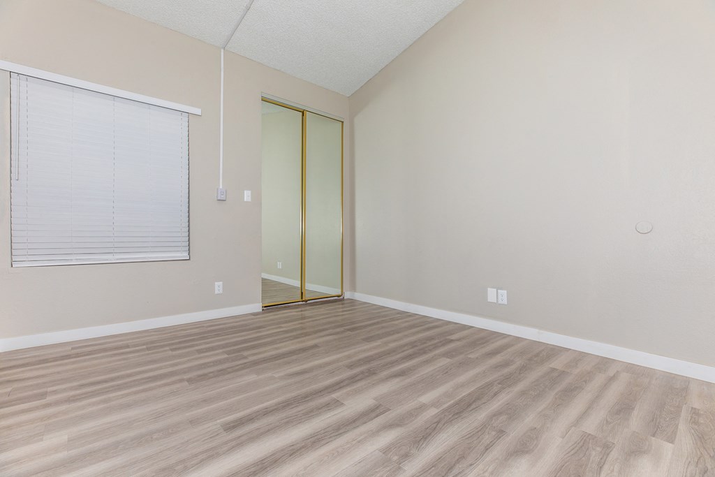 a bedroom with hardwood floors and a large window