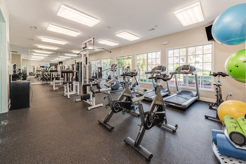 a spacious fitness center with cardio equipment and windows