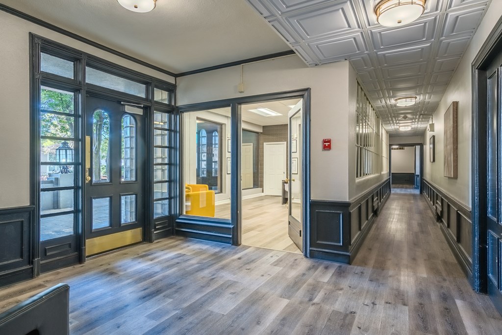 a hallway with wood floors and glass doors and a yellow chair
