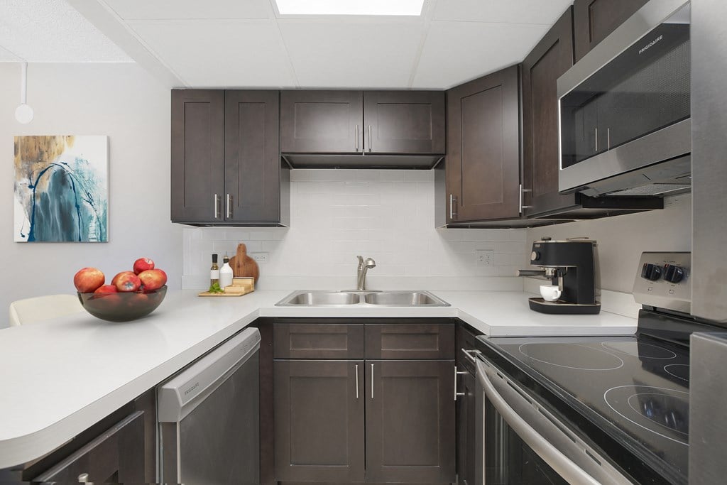 a kitchen with dark cabinets and white counter tops and a sink