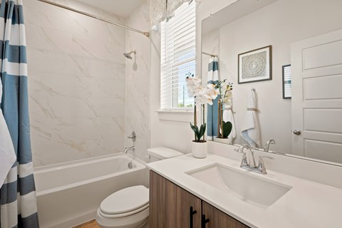 A bathroom with a white sink, toilet, and a shower with a striped shower curtain.
