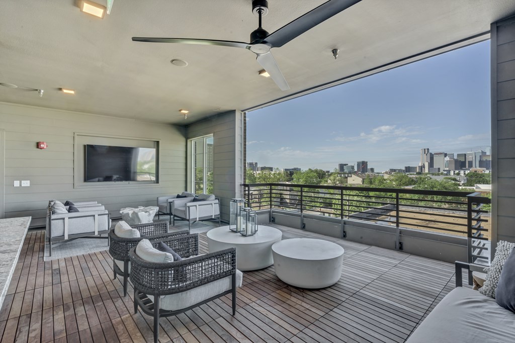A patio with a ceiling fan and a view of the city.