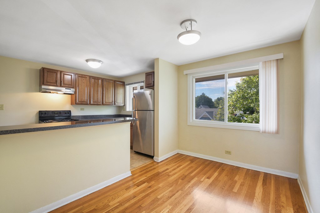an empty kitchen with a window and a stainless steel refrigerator