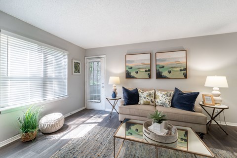 A living room with a couch, a table, and two paintings on the wall.