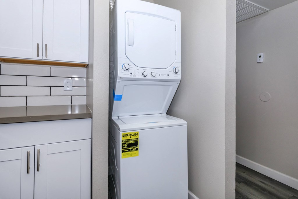 a white washer and dryer in a kitchen with white cabinets