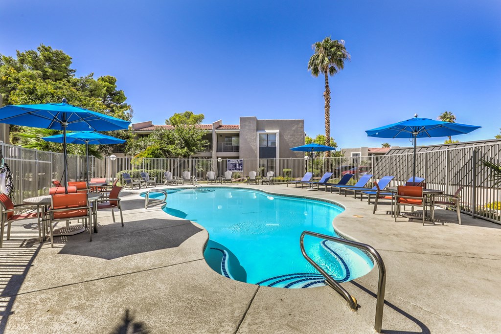 our resort style swimming pool is surrounded by patio furniture and umbrellas