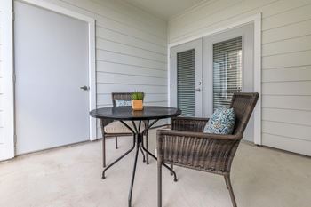 A patio with a round table and a wicker chair.