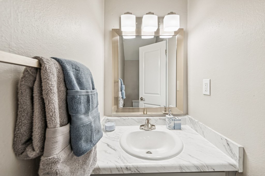 A bathroom with a marble sink and a mirror above it.