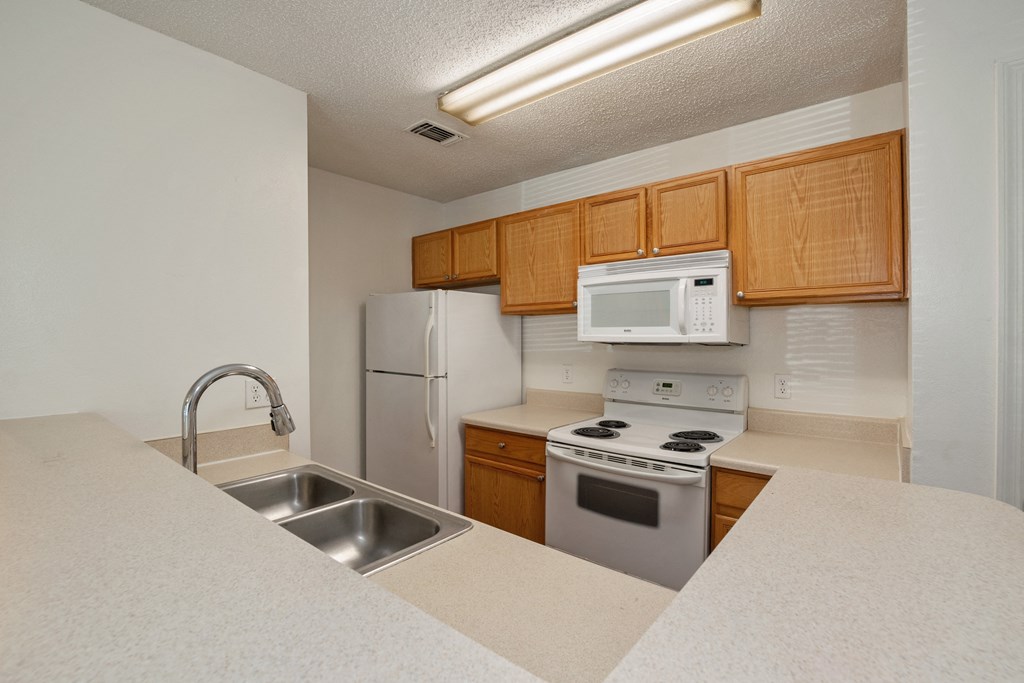 A kitchen with white appliances and wooden cabinets.