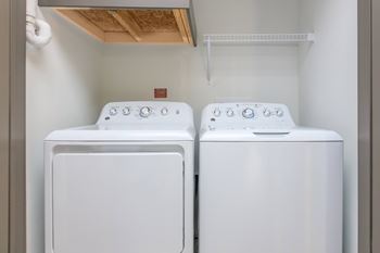 Two white front loading washing machines in a small laundry room.