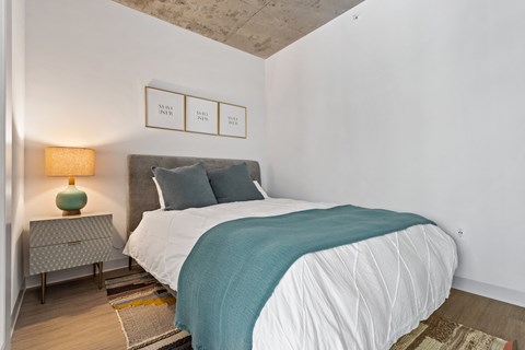 a bedroom with white walls and a bed with a blue blanket