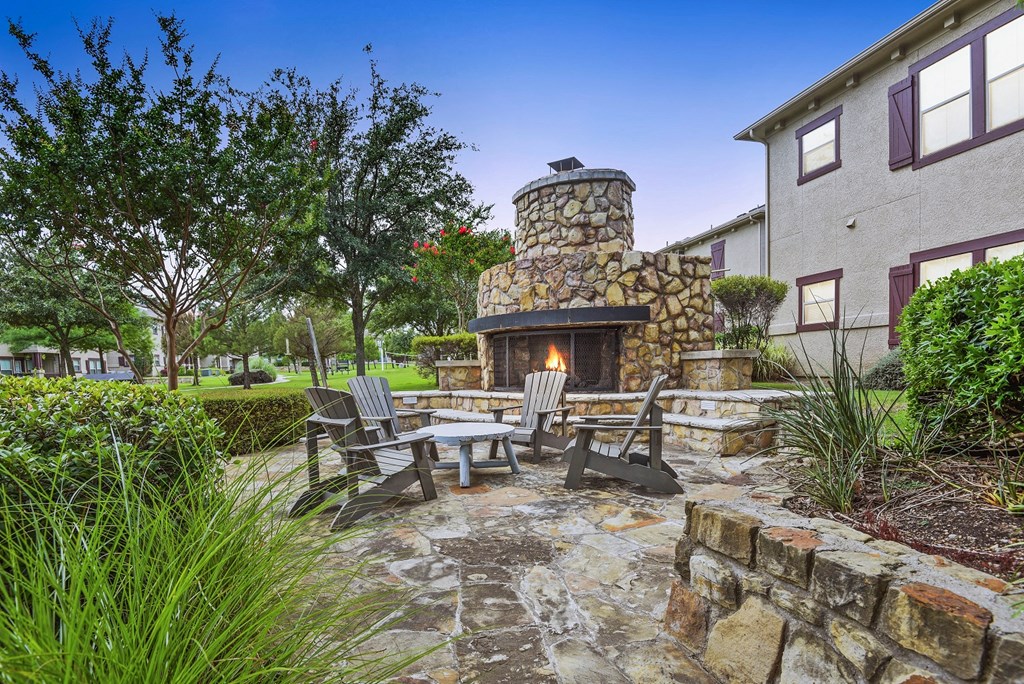a patio with a stone fireplace and a table and chairs