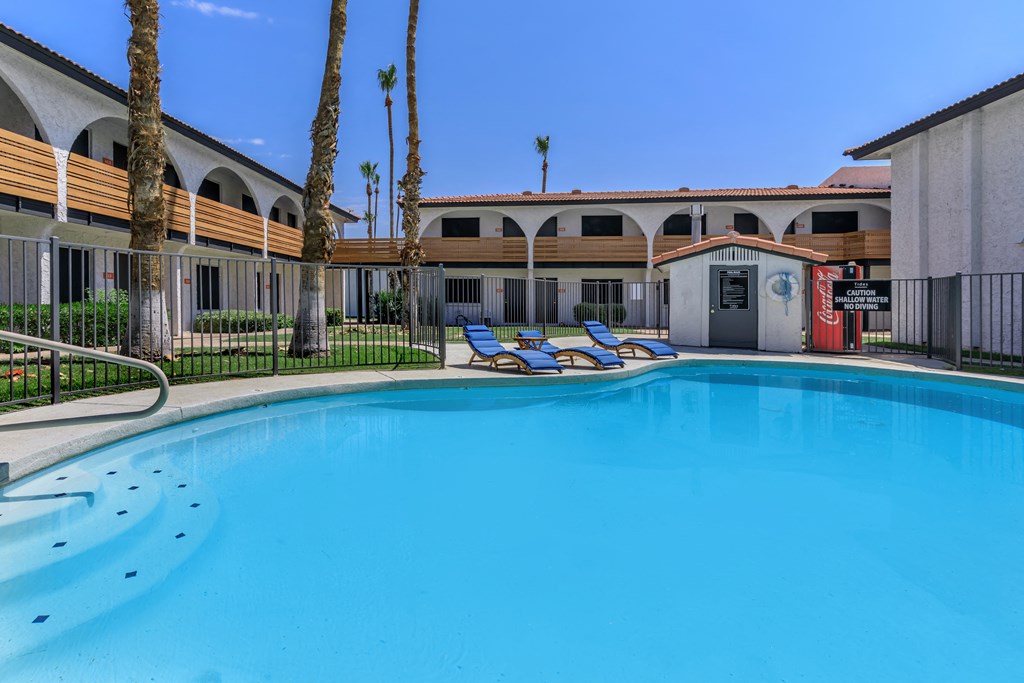 a swimming pool with lounge chairs and a building in the background
