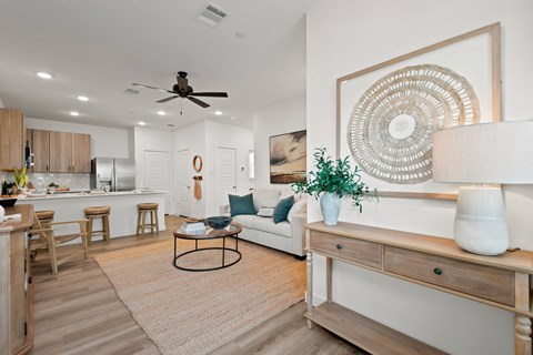 A living room with a white couch, a coffee table, and a large decorative piece on the wall.