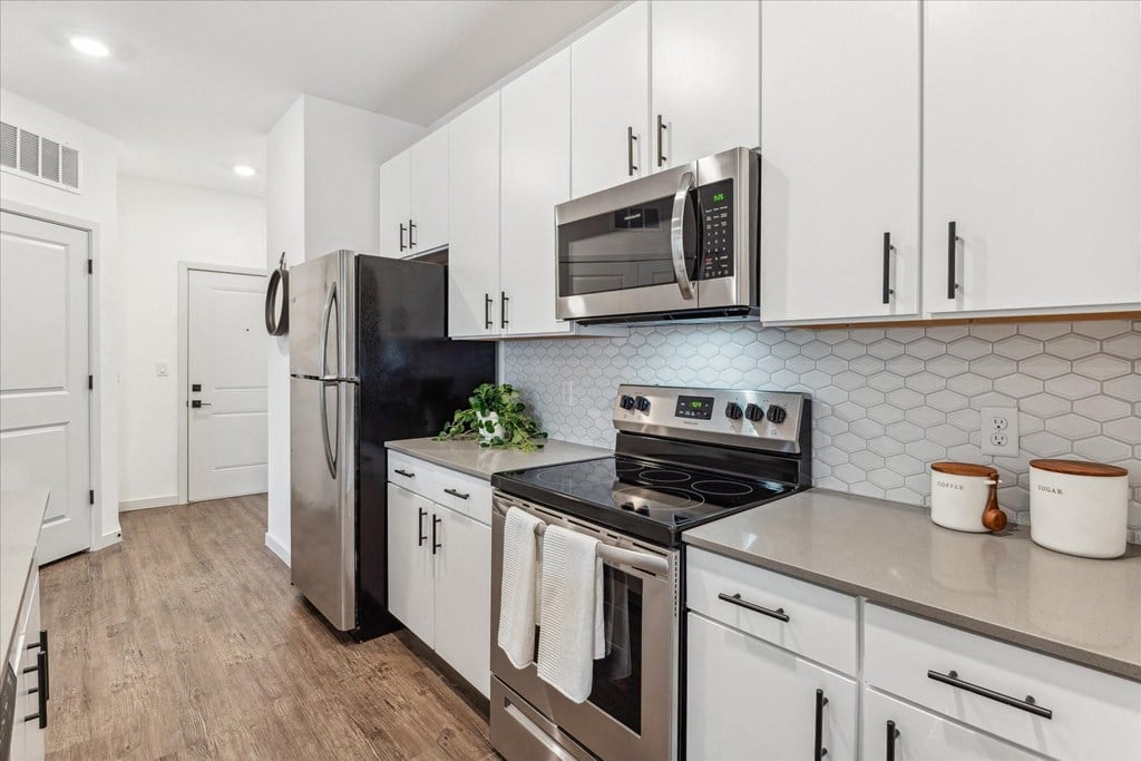 a white kitchen with stainless steel appliances and white cabinets