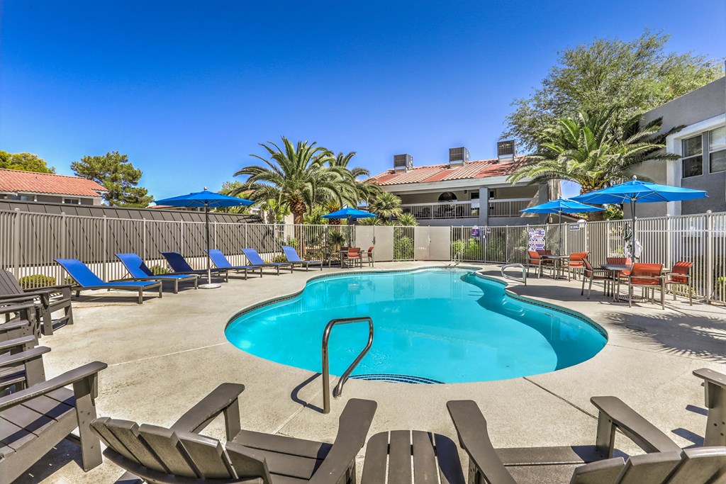 our resort style swimming pool is surrounded by chairs and umbrellas