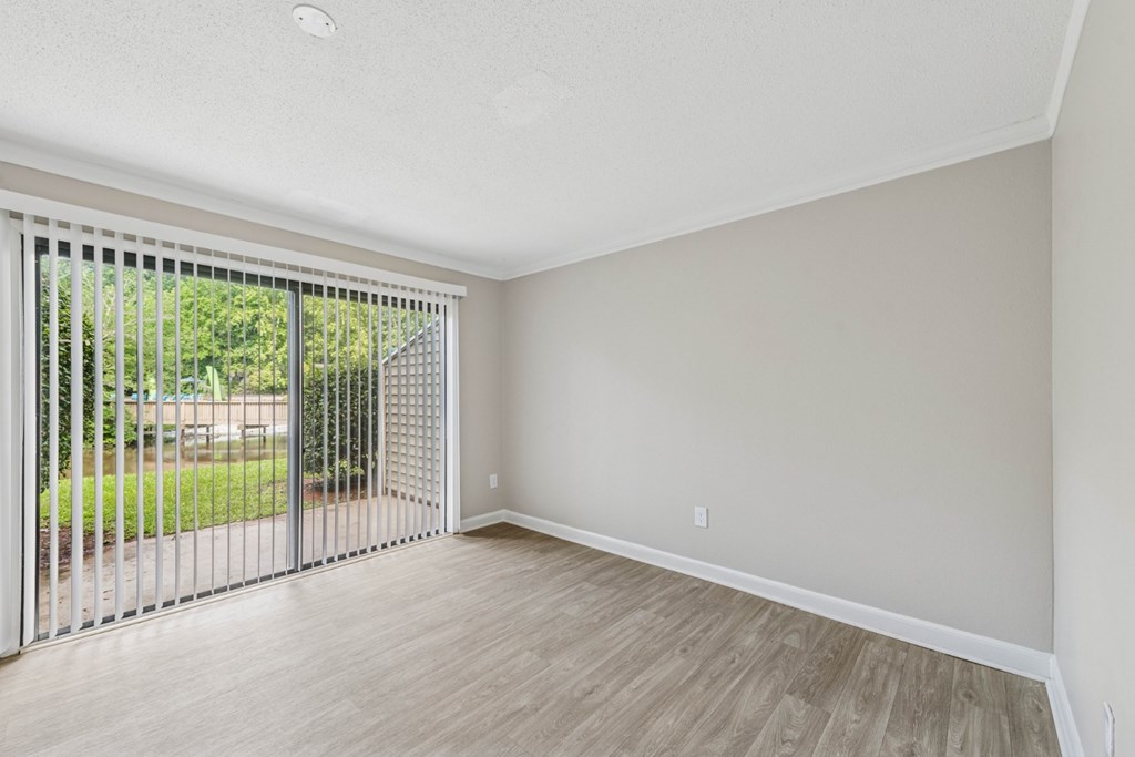 A room with a sliding glass door and wooden flooring.